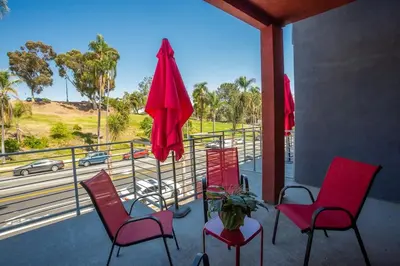 a porch with chairs and a table and a red umbrella at Spacious Studio with Incredible Balboa Park View in San Diego