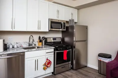 a kitchen with white cabinets and a stainless steel refrigerator at 1 Bedroom Apartment with Luxurious Design in SD in San Diego