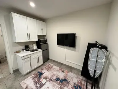 a small kitchen with white cabinets and a flat screen tv at Studio with Private Entrance next to Balboa Park in San Diego