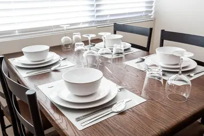 a wooden table with white dishes and glasses on it at The Most Beautiful Bay View from 1 Bedroom Apt in San Diego