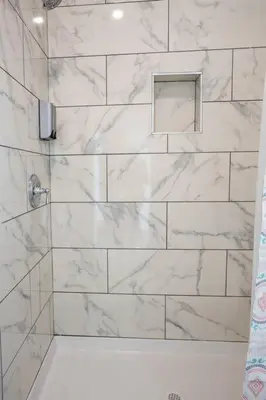 a bathroom with a shower with white marble tiles at Premier Location with Great Scenic Downtown View in San Diego