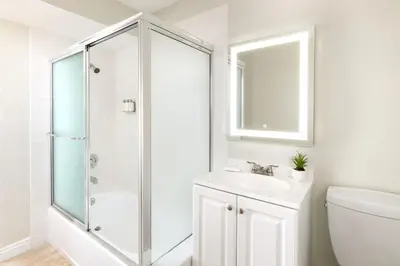 a white bathroom with a shower and a sink at Pacific Edge Hotel in Laguna Beach