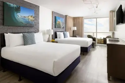 a hotel room with two beds and a desk at Pacific Edge Hotel in Laguna Beach