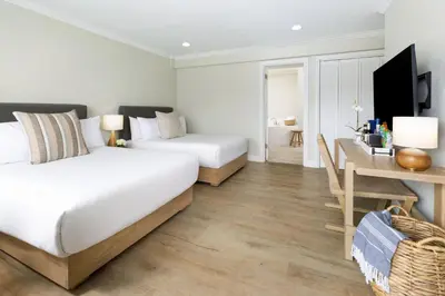 two beds in a hotel room with a desk and a desk at Pacific Edge Hotel in Laguna Beach