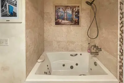a white bath tub in a bathroom with a painting at Colorful El Cajon Gem Deck, Garden and Valley Views in El Cajon