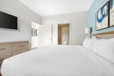 a white bedroom with a large bed and a flat screen tv at Hilton Vacation Club Riviera Beach & Shores in Capistrano Beach