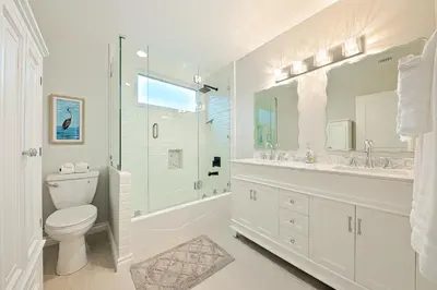 a white bathroom with a toilet and a tub and a sink at Enchanting Cottage By the Sea in Carlsbad
