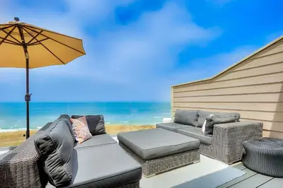 a patio with a couch and chairs and an umbrella at Seabluffe Ocean Spray in Encinitas