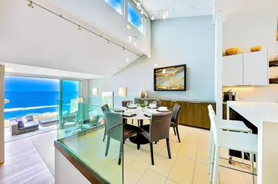 a dining room and kitchen with a glass table and chairs at Seabluffe Ocean Spray in Encinitas