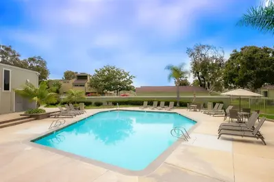 a large swimming pool with chairs and an umbrella at Seabluffe Ocean Spray in Encinitas