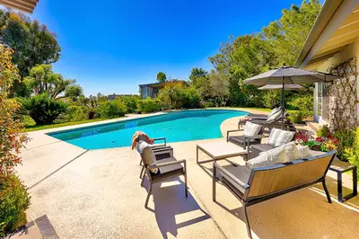 a patio with chairs and an umbrella and a pool at La Jolla Scenic Retreat in San Diego