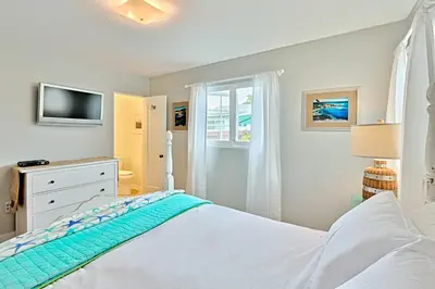 a white bedroom with a bed and a window at Seashell Cottage in San Diego
