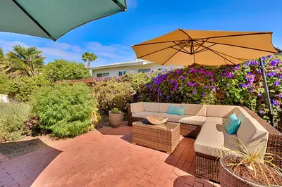 a patio with a couch and an umbrella at Seashell Cottage in San Diego