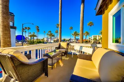 a balcony with chairs and palm trees and palm trees at Great Balboa Peninsula Combo in Newport Beach
