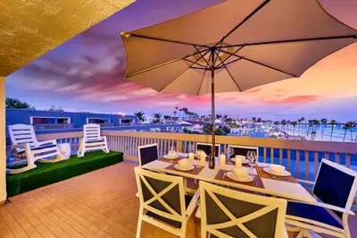 a patio with a table and an umbrella on a balcony at Pier View Retreat in Oceanside