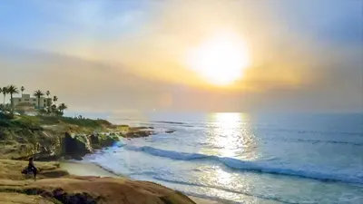 a person riding a bike on the beach at sunset at Inn by the Sea, La Jolla in San Diego