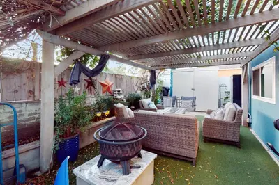 a patio with a wooden pergola with a couch and a grill at Pacific Beach Cottage in San Diego