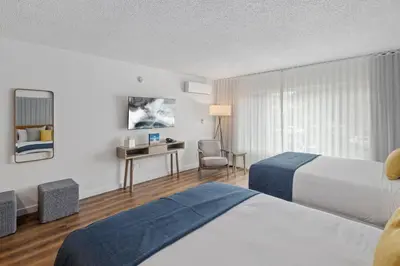 a hotel room with two beds and a desk at Sea Harbor Hotel - San Diego in San Diego