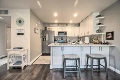 a kitchen with white cabinets and a kitchen island with stools at Contemporary San Diego Gem with Community Pool! in San Diego