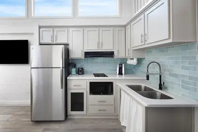 a kitchen with white cabinets and a stainless steel refrigerator at Sun Outdoors San Diego Bay in Chula Vista
