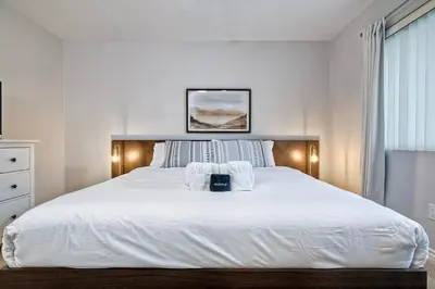 a bedroom with a large white bed with towels on it at 90 Walk Score - Steps to Beach & Dining - Reserved Parking in Carlsbad