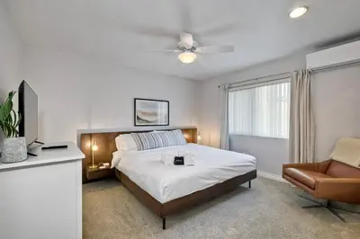 a bedroom with a bed and a chair and a window at 90 Walk Score - Steps to Beach & Dining - Reserved Parking in Carlsbad