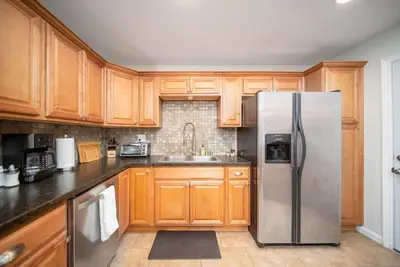 a kitchen with wooden cabinets and a stainless steel refrigerator at 4 BR Home with Game Room! Family Friendly! Centrally Located! in San Diego