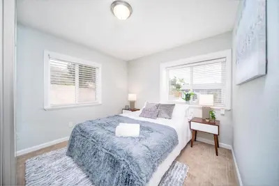 a white bedroom with a bed and two windows at 4 BR Home with Game Room! Family Friendly! Centrally Located! in San Diego