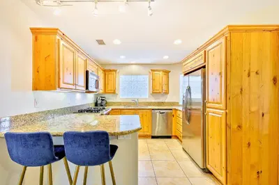 a kitchen with wooden cabinets and blue bar stools at Crown Point Views Home in San Diego