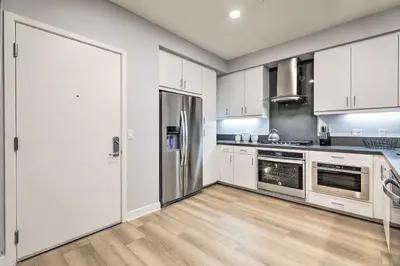 a kitchen with white cabinets and stainless steel appliances at Modern Irvine Condo with Pool - 7 Mi to Beach! in Irvine
