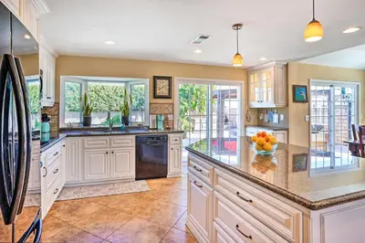 a kitchen with white cabinets and granite counter tops at Deluxe Laguna Hills Home with Outdoor Oasis! in Laguna Hills