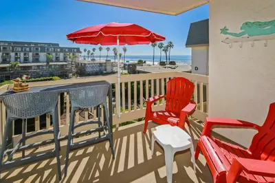 a balcony with chairs and a table and an umbrella at C212 - Sand Tropez in Oceanside