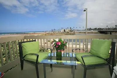 a table and two chairs on a balcony with the beach at G32 - Harbor Cottage - On-the-Sand in Oceanside