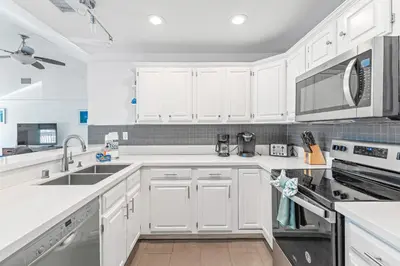 a white kitchen with white cabinets and appliances at Felspar Sanctuary in San Diego