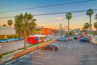 a parking lot with cars and a red bus at Felspar Sanctuary in San Diego