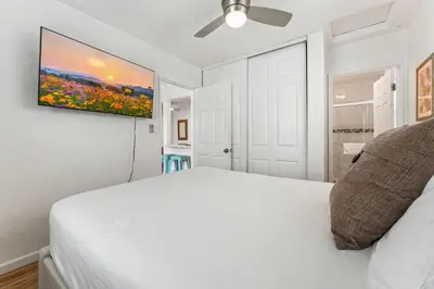 a bedroom with a white bed and a painting on the wall at La Jolla Beach Casita in San Diego
