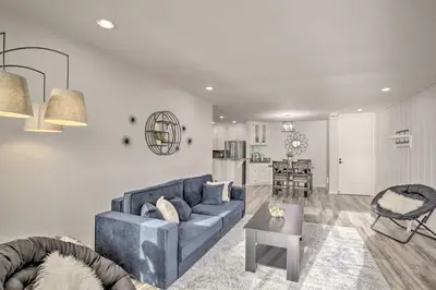 a living room with a blue couch and a kitchen at Charming Oceanside Condo with Beach and Pool Access! in Oceanside
