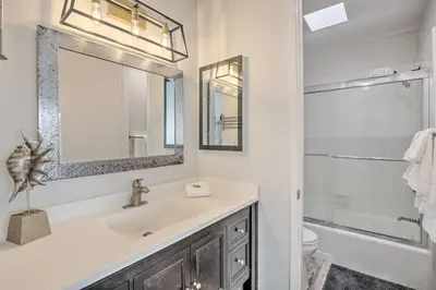 a bathroom with a sink and a toilet and a mirror at Charming Oceanside Condo with Beach and Pool Access! in Oceanside
