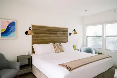a bedroom with a large white bed and a chair at SCP Seven4One Hotel in Laguna Beach