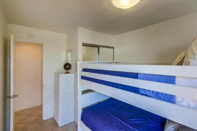a bedroom with a white bunk bed with blue sheets at Cohasset Getaway Unit #3 in San Diego
