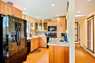 a kitchen with wooden cabinets and a black refrigerator at Canyon Palms in San Diego