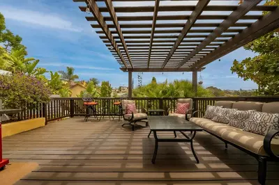 a deck with a couch and tables and chairs at Canyon Palms in San Diego