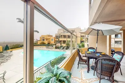 a balcony with a table and chairs and a swimming pool at Ocean Pointe Lagoon 107 - 30 Night Minimum in Carlsbad
