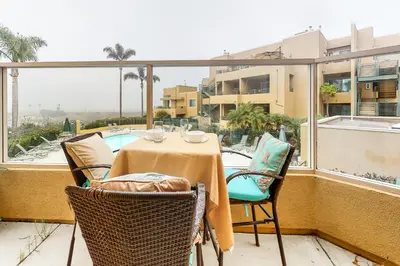 a table and chairs on a balcony with a view of a pool at Ocean Pointe Lagoon 107 - 30 Night Minimum in Carlsbad