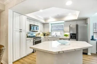 a kitchen with white cabinets and a large island at Carlsbad Village Charm in Carlsbad