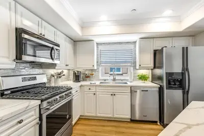 a kitchen with white cabinets and a stainless steel refrigerator at Carlsbad Village Charm in Carlsbad