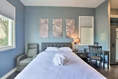 a bedroom with a large white bed and a chair at Torrey Spa Suite Modern San Diego Studio! in San Diego