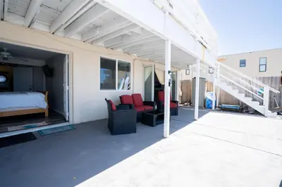 a room with a bed and two chairs on a patio at BEACHFRONT COTTAGE LOWER UNIT in Oceanside