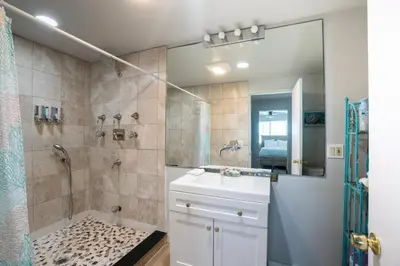 a bathroom with a shower and a sink and a mirror at BEACHFRONT COTTAGE LOWER UNIT in Oceanside