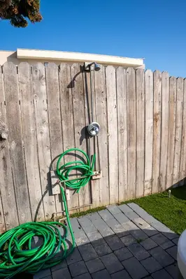 a fence with a green hose hooked up to it at BEACHFRONT COTTAGE LOWER UNIT in Oceanside